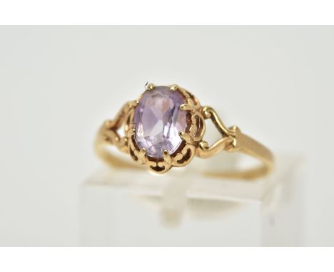 A 9CT GOLD AMETHYST RING, designed with a claw set, oval cut amethyst within an open work gallery, bifurcated scroll detailed