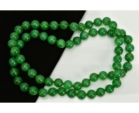A JADE BEADED NECKLACE, dyed green circular beads, on a green cord, each bead measuring approximately 12mm, length 840mm, app