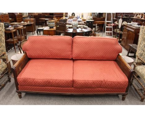 An Edwardian mahogany three seater Bergere sofa, printed red linen upholstery and squab cushions, raised on turned fluted fro