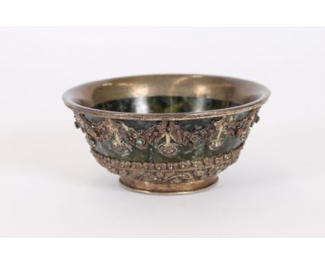 A spinach green jade bowl, possibly Tibetan, having overlaid applied white metal and jeweled decoration, 12.5cm dia. 