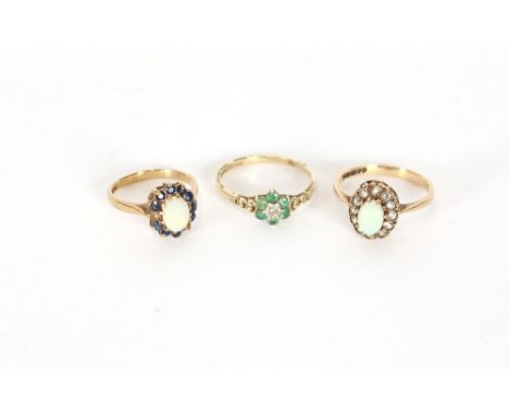 A 9ct gold emerald and diamond set ring; a 9ct gold opal ring surrounded by white stones; and a 9ct gold opal ring surrounded