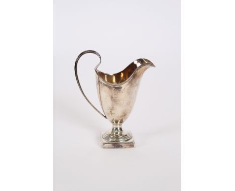 An Edwardian silver helmet shaped cream jug, having reeded handle and raised on a square plinth, Birmingham 1909, 13cm high