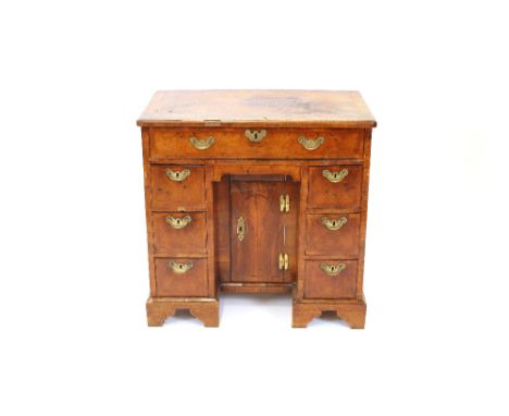 An 18th Century walnut kneehole desk, the cross-banded top above a single drawer and blind frieze drawer, recessed cupboard a