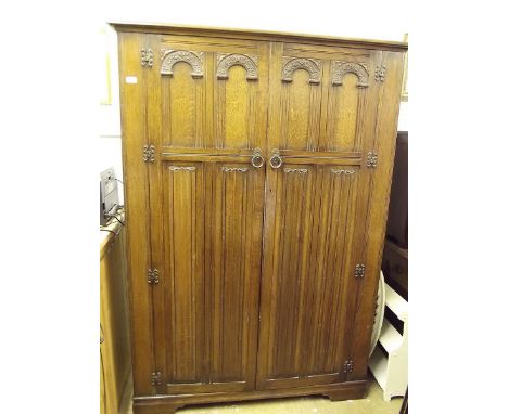 An oak linen fold carved bedroom suite comprising: two door wardrobe, compartum, dressing table and pot cupboard