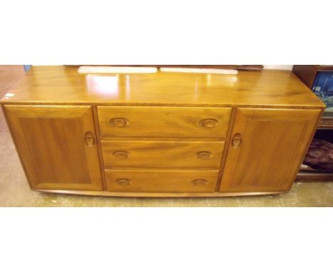An Ercol elm sideboard with three drawers flanked by cupboards 