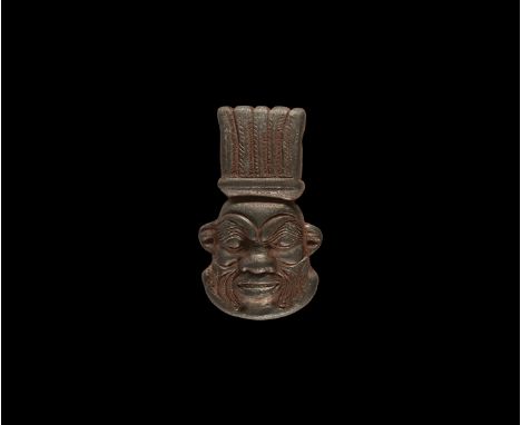 New Kingdom, 1550-1070 BC. A carved haematite pendant mask of Bes with plumed headdress and grotesque features, pierced trans