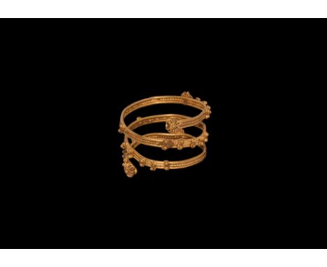 Roman Period, 30 BC-323 AD. A gold finger ring comprising a flat-section shank of ropework between filigree edges, applied ro