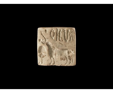 2nd millennium BC. A square limestone seal with pierced lug to the reverse, intaglio design of a zebu with script above.  24 