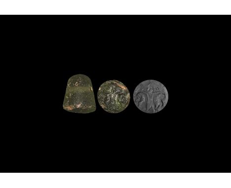 1st millennium BC. A conical green glass seal with rounded top, intaglio standing figure flanked by profile busts. 4.16 grams
