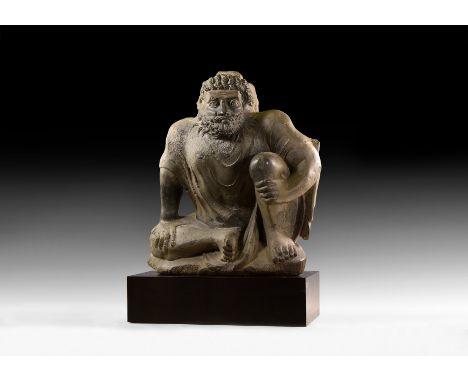 3rd-5th century AD.&nbsp;Atlas at rest carved in schist, crouching on one knee with a muscular torso, stern facial expression