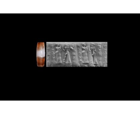 19th-16th century BC. A banded agate cylinder seal comprising: a robed king, wearing a cap and raising one hand, faces the as