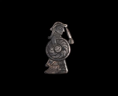 9th-10th century AD. A silver pendant of a female in floor-length robe holding a shield in her right hand and drawn knife in 