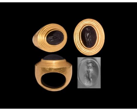 Late 4th-early 3rd century BC. A gold ring comprising a D-section shank and broad bezel with tiered upper face and central ce