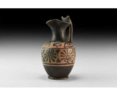 6th-4th century BC. A ceramic black-figure oinochoe ewer with flared foot, bulbous body, tubular neck with trefoil lip, strap