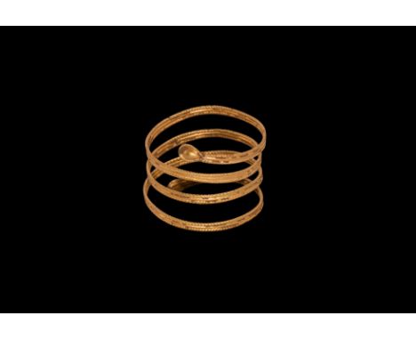 Ptolemaic Period, 332-30 BC. A gold ring comprising a hoop of four coils of filigree ropework, piriform bulb finials with fil