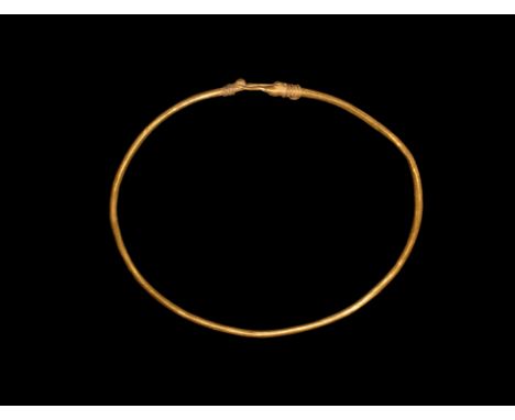 5th-3rd century BC. A round-section gold neck or arm ring with the ends coiled about the shank, granule stud.  15 grams, 10cm