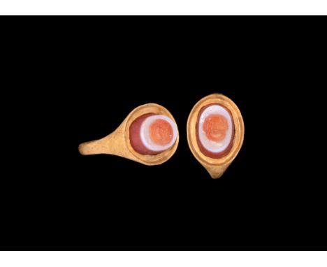 2nd-3rd century AD. A gold finger ring comprising a D-profile hoop, ellipsoid bezel with flange rim, inset banded carnelian c
