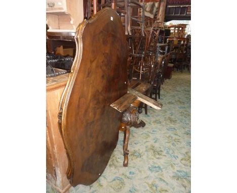 An Italian dining table in walnut with shaped outline raised on a carved pillar and quadruped base