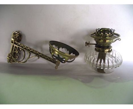 A good quality oil burning lamp with rising burner marked Harrods, with a clear cut glass bowl set within a brass wall bracke