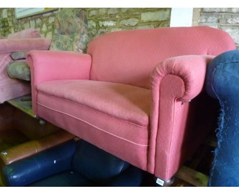 A small Edwardian two seat cottage sofa with scrolled arms and back on bun feet