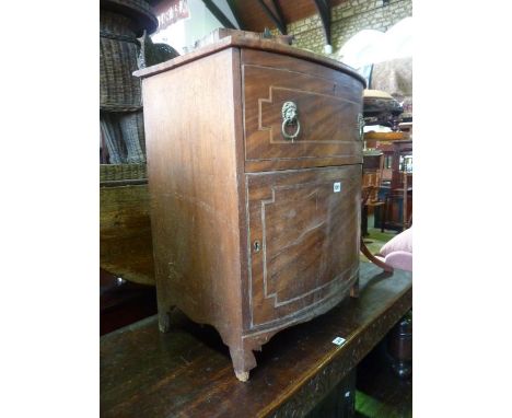 A Georgian mahogany bow fronted commode with rising cover, the front elevation with string inlaid detail and lion mask and ri