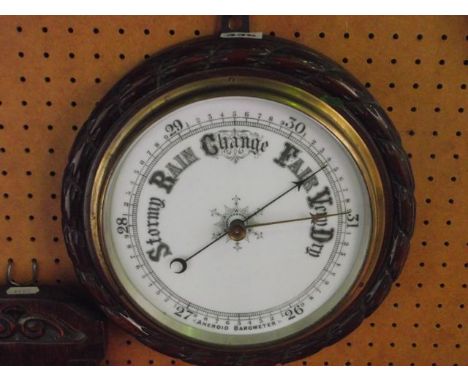 An Edwardian aneroid barometer, the circular case with carved rope twist border and ceramic dial