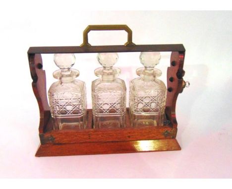 A late 19th/early 20th century oak cased three divisional decanter with silver plated mounts and locking handle containing a 