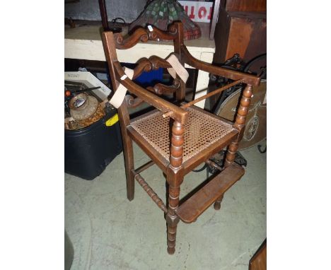 A child's high chair in the Carolean style with ladderback, turned bobbin supports, cane work seat, etc