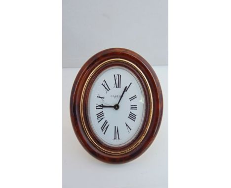 A Cartier Pendulette travel alarm clock in an oval tortoiseshell style frame 7509 15867, complete with a red leather and gilt