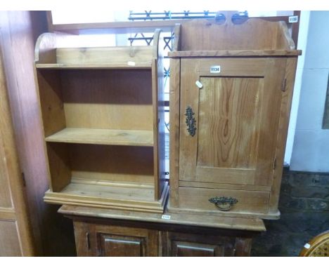 A continental stripped pine hanging cupboard with panelled door and single drawer and a further pine hanging shelf