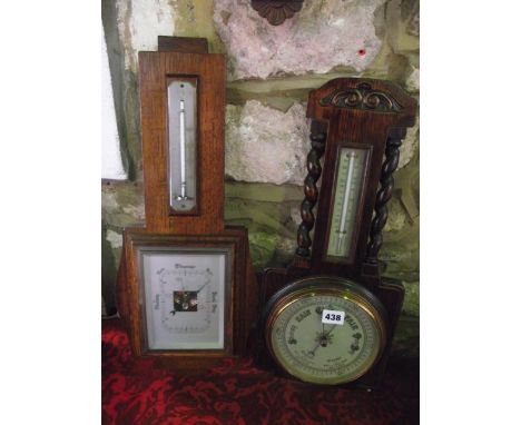 An Edwardian aneroid barometer in an oak case with barley twist supports, and a further Art Deco example
