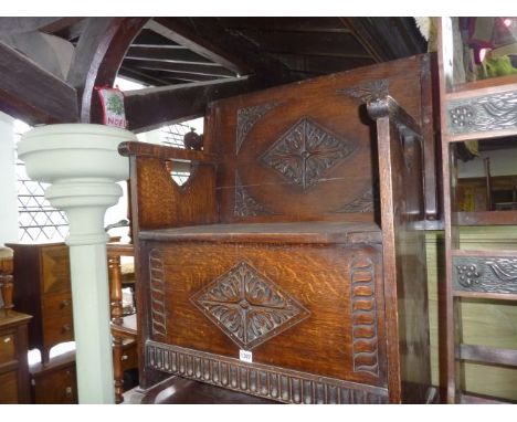 An Edwardian oak monks bench/settle with carved detail with hinged top/back, 68 cm wide