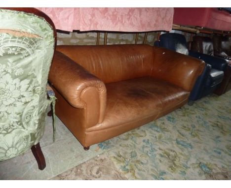 A contemporary three seat sofa upholstered in a pale brown leather on turned supports