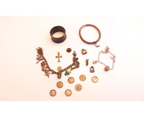 Two charm bracelets, hung with various silver and white metal charms, and four further loose charms; an English silver napkin