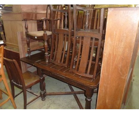 An oak draw leaf dining table on four turned supports united by x shaped stretchers together with a set of five (4&1) oak din