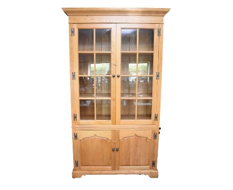 A large light oak display cabinet by Venables Brothers, Cheswardine, the ogee cornice and plain frieze above twin glazed door