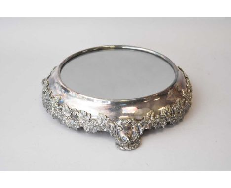 A 19th century silver plated mirrored stand, with vine and leaf decoration and raised on three scroll bracket feet, 41cm diam