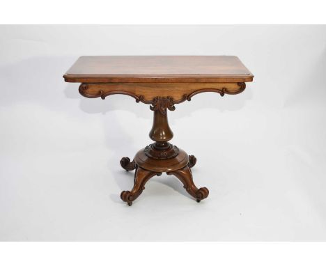 A Victorian rosewood fold-over card table, the moulded top above a shaped frieze with scroll and leaf moulding, on a baluster