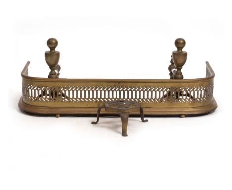 A PIERCED BRASS FENDER 76.5cm wide together with a pair of fire dogs with turned finials and a pierced brass three legged tri