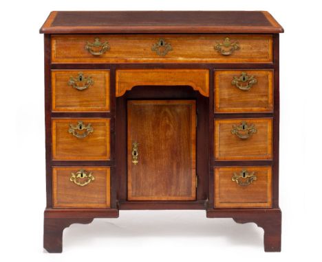 A GEORGIAN MAHOGANY KNEE HOLE DESK with satinwood crossbanded top, eight drawers around a central kneehole with cupboard with