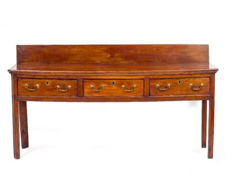 A GEORGE III FRUITWOOD DRESSER BASE with a raised back, three drawers with brass swan neck handles and raised in square cante