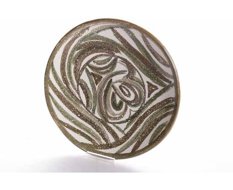 20TH CENTURY STUDIO POTTERY CIRCULAR PLAQUE ATTRIBUTED TO WILLIAM MARSHALLpainted in shades of brown and green on a white gro