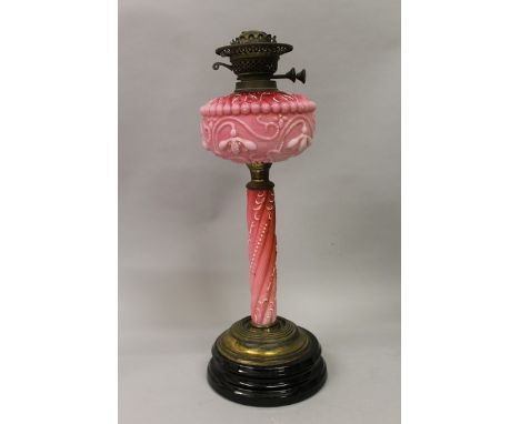 A VICTORIAN OPAQUE COLOURED GLASS OIL LAMP on a circular wooden base 21ins high.