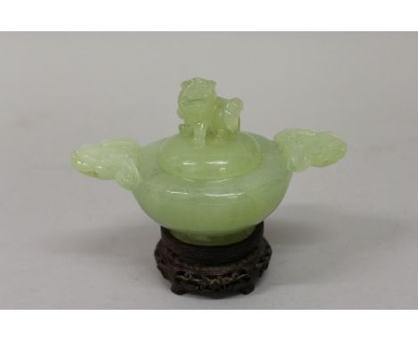 A CHINESE GREEN JADE TWO HANDLED KORO AND COVER on a wooden stand 3ins high.