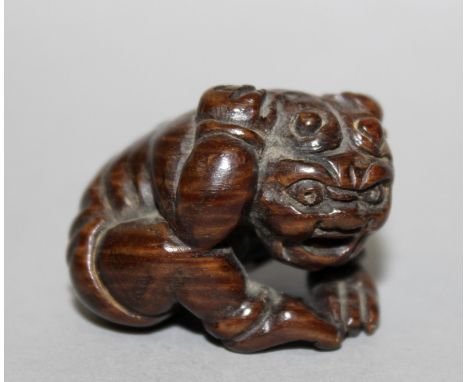 A 19TH/20TH CENTURY JAPANESE CARVED WOOD NETSUKE OF AN ONI, unsigned, the demon seated in fear with its hands clasped over it