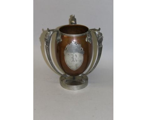 A PAIRPOINT MIXED METAL THREE HANDLED CHALLICE CUP with mask handle and oval cartouche, engraved R 10ins high.