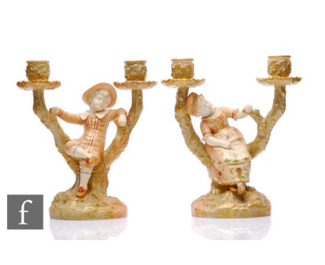 A pair of Royal Worcester blush ivory twin branch candlesticks, circa 1906, modelled as children sitting among forked branche