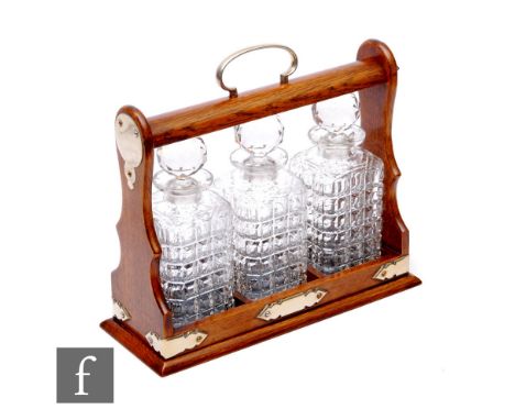 A late 19th Century oak tantalus, fitted with three decanters, plated mounts, width 35cm.