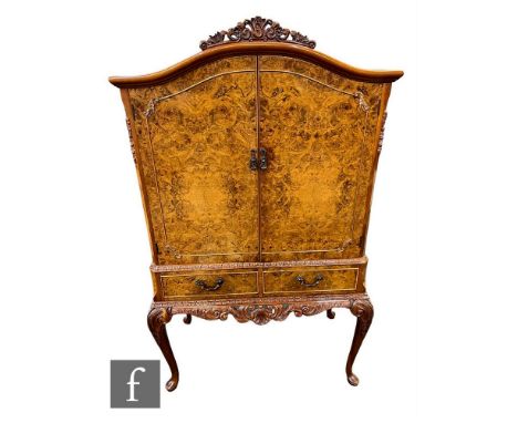 A Queen Anne style carved walnut cocktail cabinet, the mirror back and glass shelf interior enclosed by a pair of figured doo
