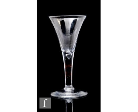 An 18th Century drinking glass, circa 1740, the drawn trumpet bowl above a solid plain stem with internal tear, raised to a c